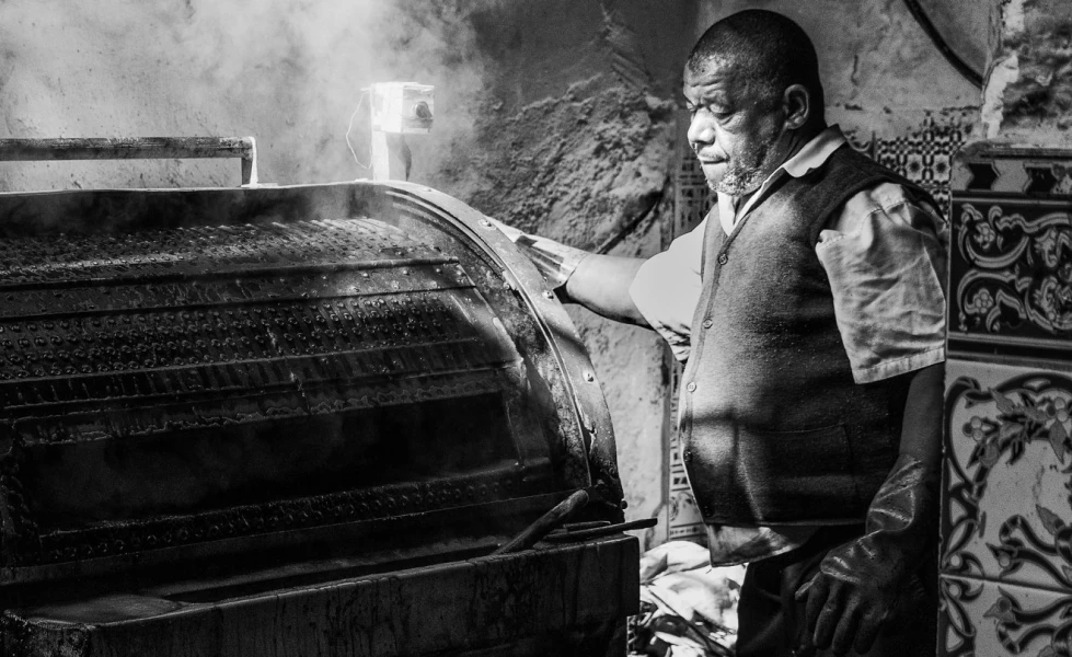 Traditionelle Ledergerbung: Dampfende altertümliche Ledertrommel bedient von einem Gerber vor ca. 60 Jahren. Historische Ledergerbung: Ein Gerber bedient eine dampfende altertümliche Ledertrommel vor ca. 60 Jahren.